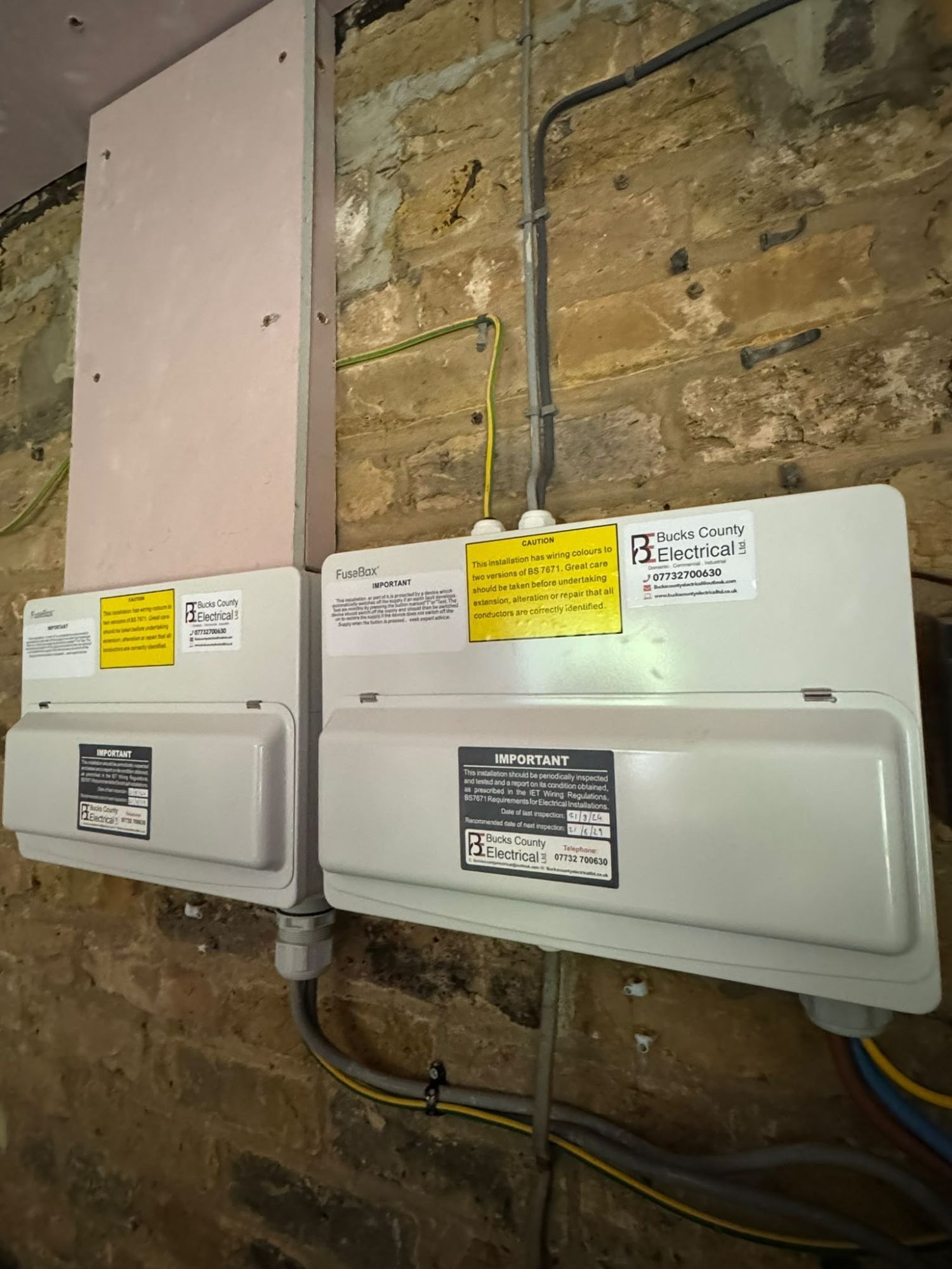 Two consumer units with Bucks County Electrical labels showing the date of last and next inspection