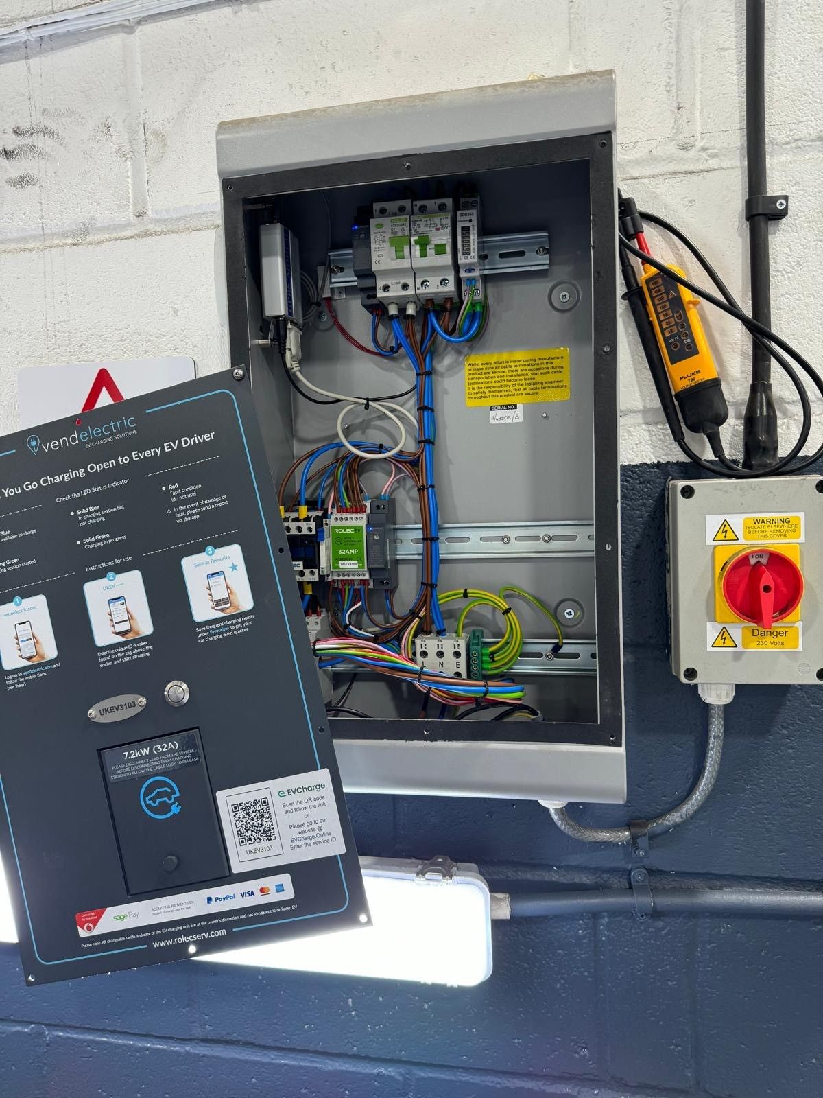 EV charge point supply with isolator and distribution enclosure on a painted wall
