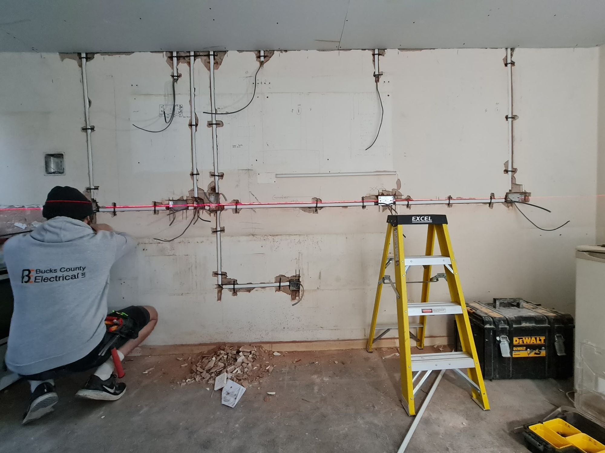 Bucks County Electrical electrician first-fixing a full wall of new conduit and back boxes during a rewire